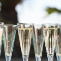 Many glasses of champagne or prosecco near resort pool in a luxury hotel. Pool party. Pouring drink into glasses. Horizontal, banner format
